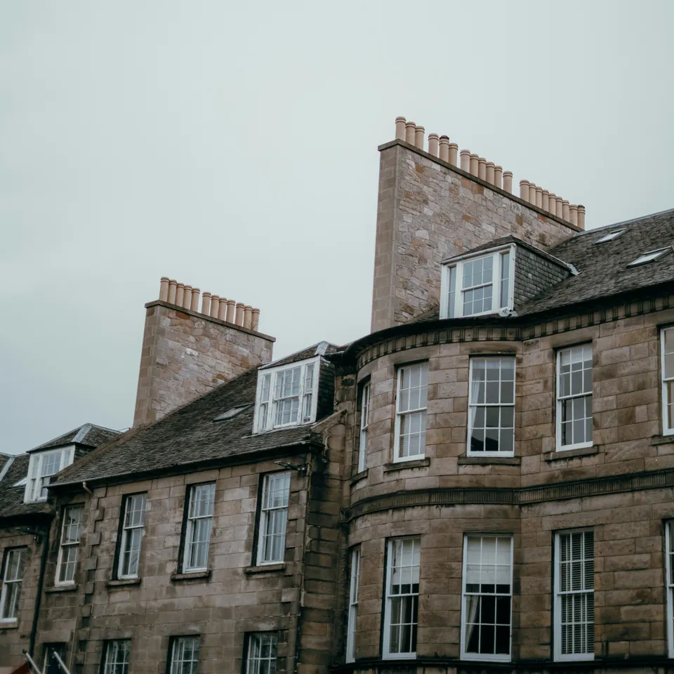 Slate roofs, dormer windows and sandstone chimney stacks on an Edinburgh terrace.